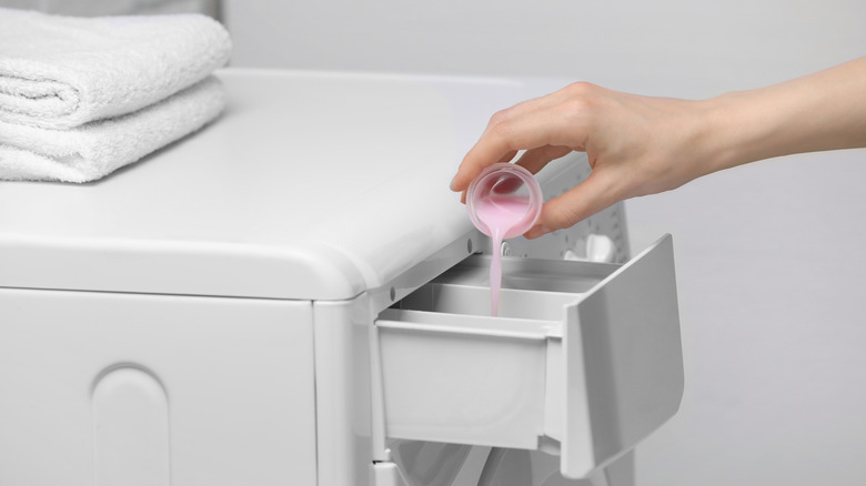 Beyaz çamaşır makinesine kumaş yumuşatıcı ekleme