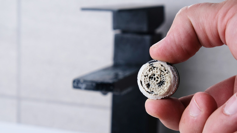 Birikme dolu kaldırılmış bir havalandırıcı tutan kişi