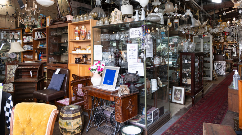 Vintage mobilya ve cam eşyalarla dolu bir tasarruf mağazasının içinde dağınık