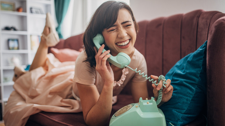 Bir kişi açık yeşil bir sabit hat telefonu kullanır