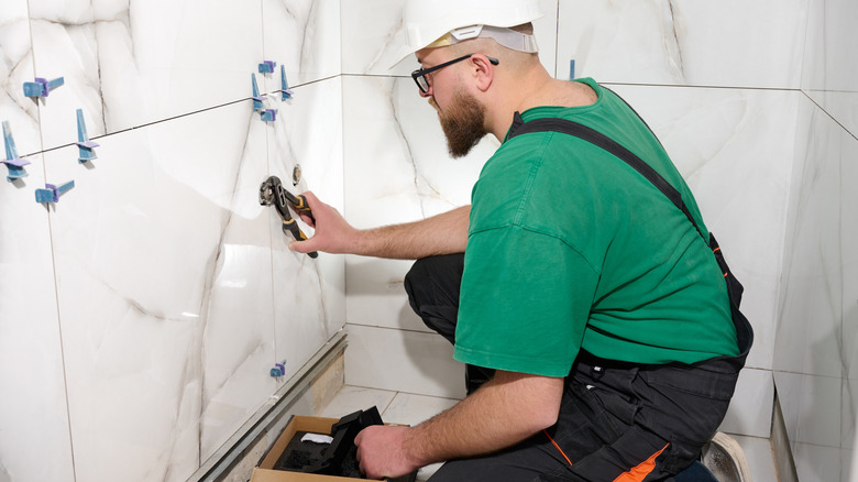 Bir adam bir banyoya el taşıyan bir bide püskürtücü kurar