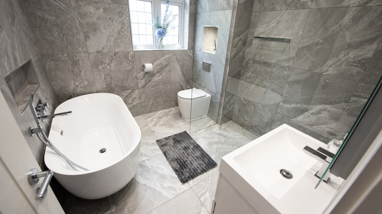 Beyaz küvet, lavabo ve zeminli gri banyo