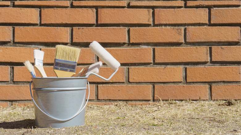 Önünde boya malzemeleri olan tuğla duvar