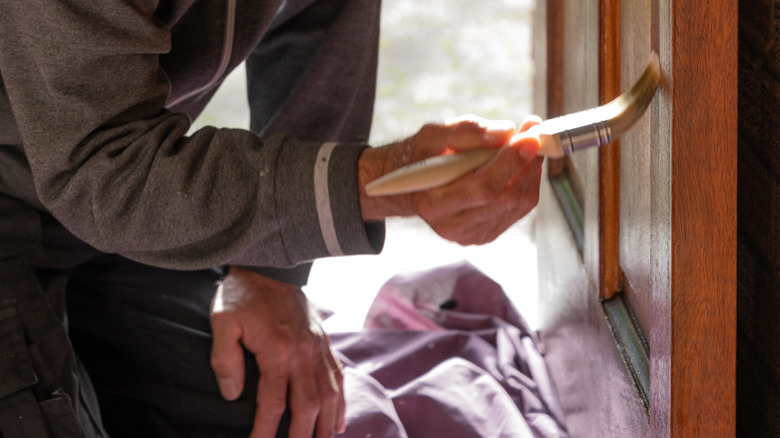 Bir adam bir boya fırçasıyla tahta bir kapı boyar