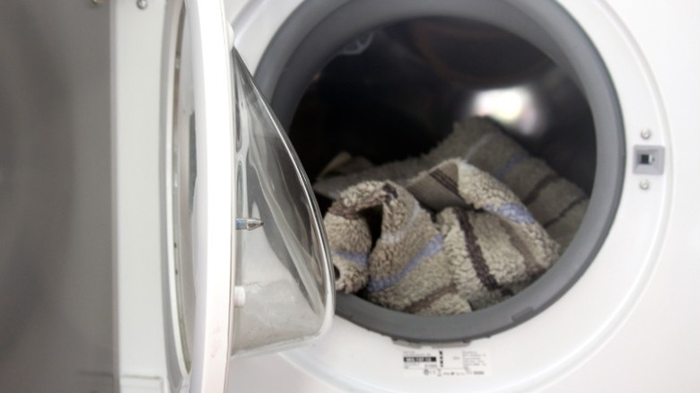 Beyaz çamaşır makinesinde oturan banyo paspası açık