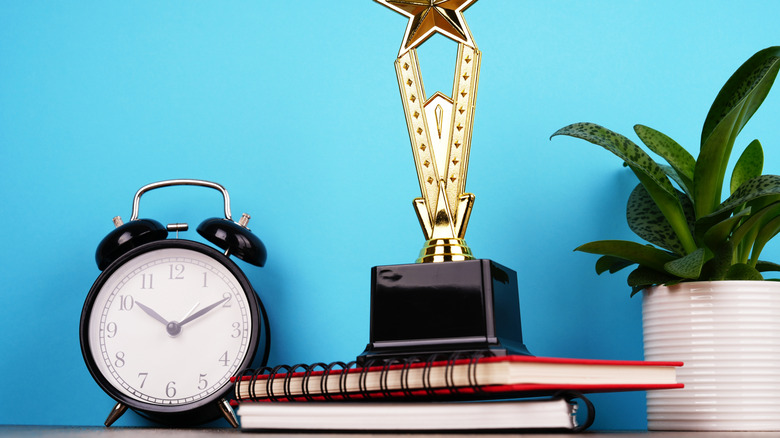 Yanında bitki ve saat ile masada spirallerin üstünde kupa