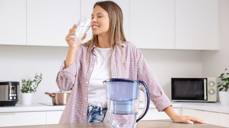 Mutfakta filtre sürahi içme suyu olan bir kişi