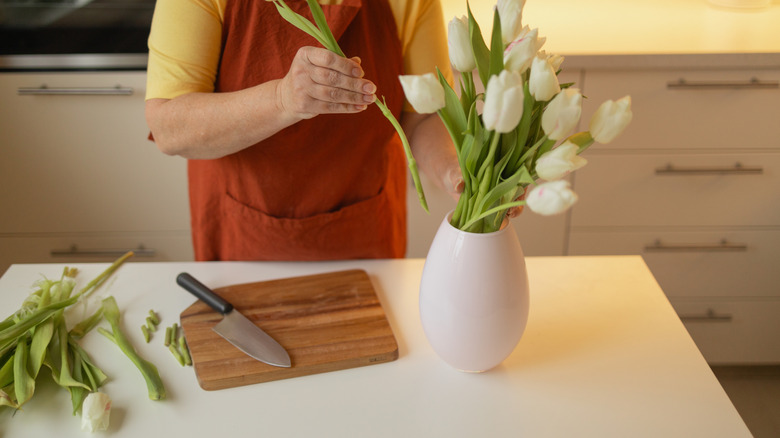 Beyaz laleler kesen ve onları vazoya yerleştiren kadın