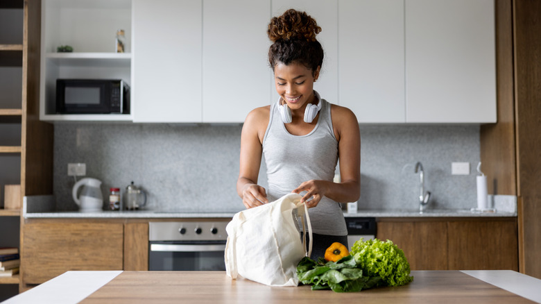 Yeniden kullanılabilir çantada yiyecekleri olan kadın