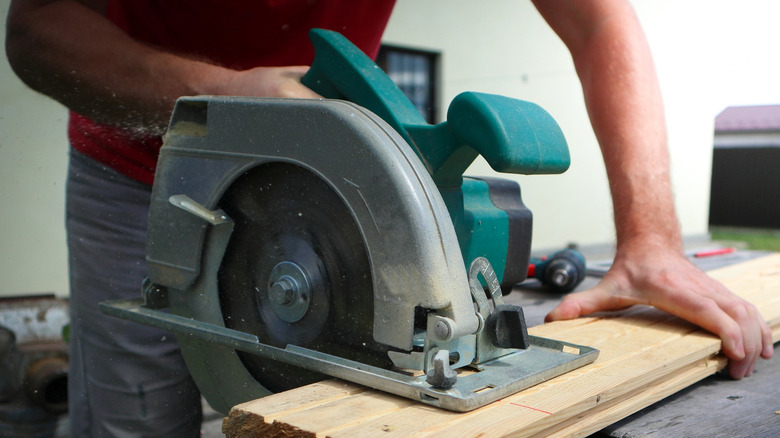 Elektrik dairesel testereleri kullanan bir adam