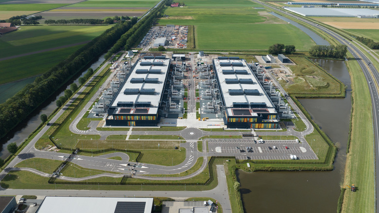 Aksi takdirde yeşil bir alanın ortasında otoparklarla çevrili iki büyük dikdörtgen veri merkezinin hava görünümü