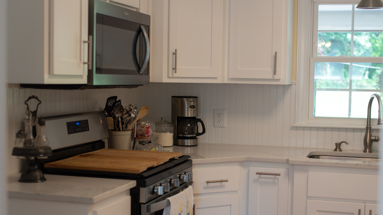 Beyaz boncuk tahtası backsplash ile beyaz bir mutfak