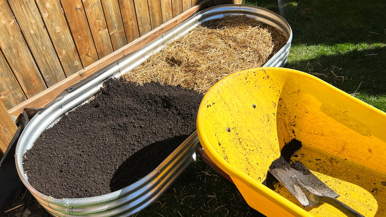 Yükseltilmiş metal kir yatağının yanında sarı bir el arabası.