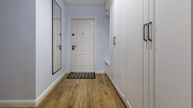 Soluk mavi duvarlar ve beyaz dolaplarla dar giriş yolu