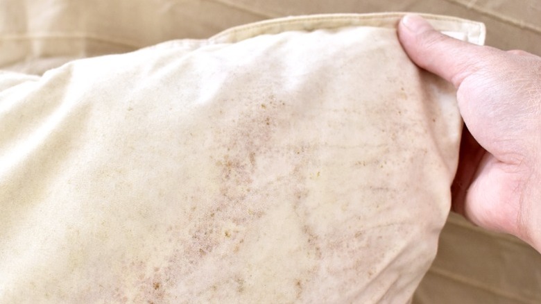 Kalıp lekeli beyaz yastığın köşesini tutan kişi