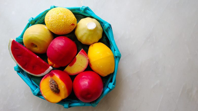 Çeşitli meyve şeklindeki sabunlar içeren mavi bir kase