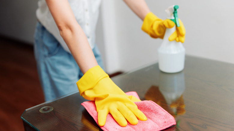 Bir masa havlu ve çözüm ile temizleyen kişi