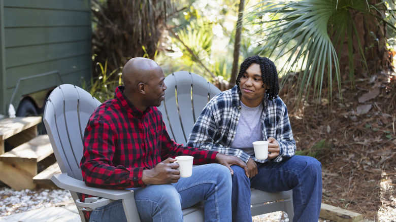 İki kişi Adirondack sandalyelerinde oturuyor ve sohbet ediyor