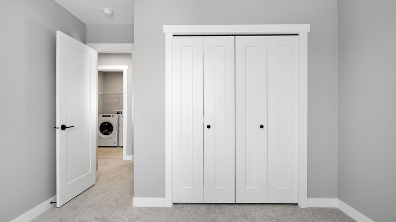 Gri bir odada beyaz dolap kapıları