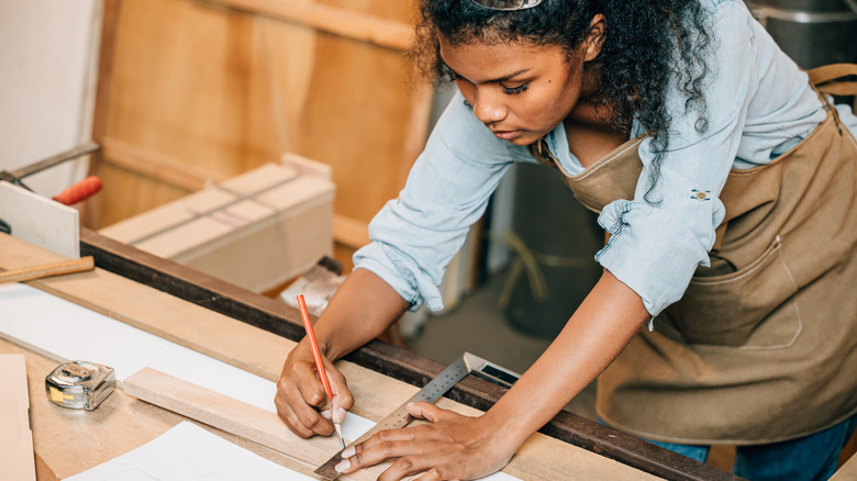 DIY için ahşap parçaları ölçen kişi