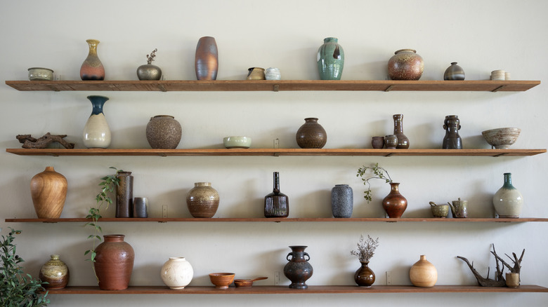 Açık ahşap raflarda vintage seramik parçalardan oluşan bir koleksiyon görüntülenir