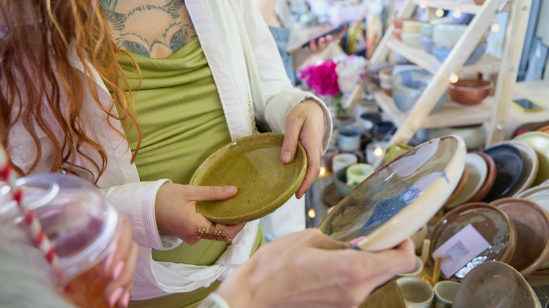 İki kişi vintage seramik plakaları tasarruflu bir dükkanda tutuyor