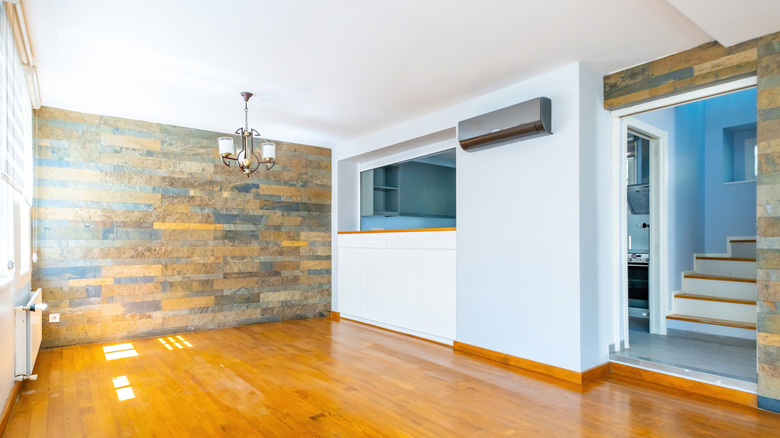 Boş bir yemek odasında ahşap kaplı bir vurgu duvarı ve mutfağın içine bir geçiş penceresi vardır.