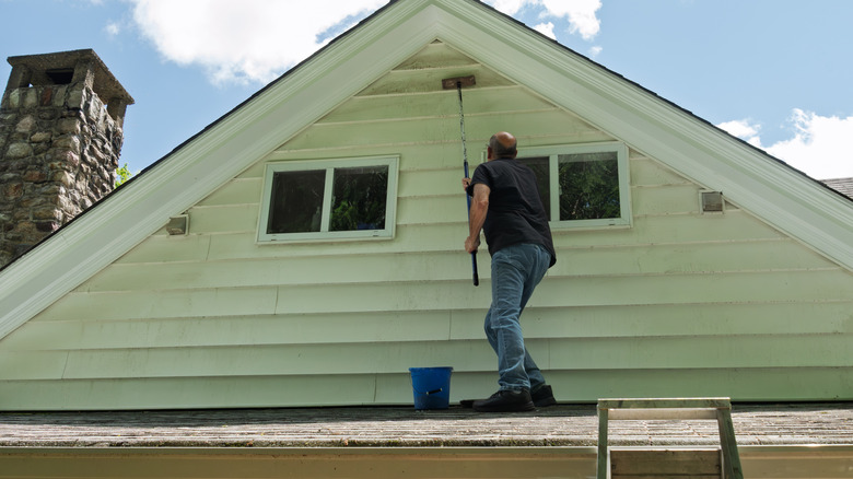 Evin altında çatı temizliği siding üzerinde duran adam