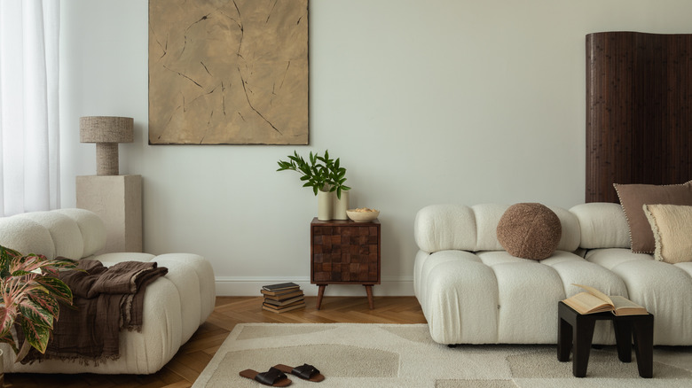 Hafif ahşap zeminli oturma odası, bej halı ve koyu ahşap aksanlar