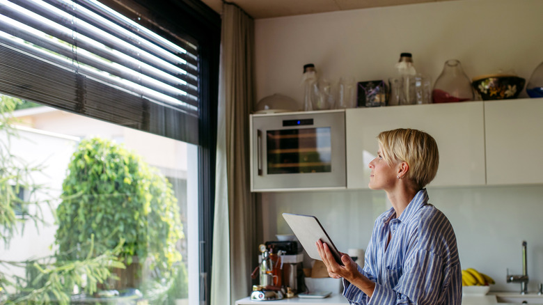 Birisi tablette bir uygulama ile akıllı panjurları kapatan biri.