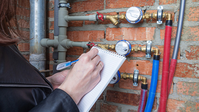 Ev sahibi su sayacını ölçüyor.