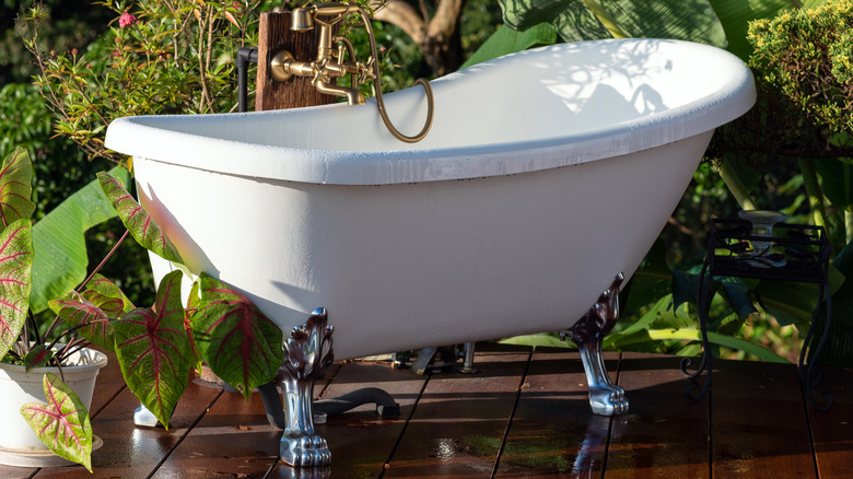 Dışarıda tahta platformda beyaz küvet bitkilerle çevrili