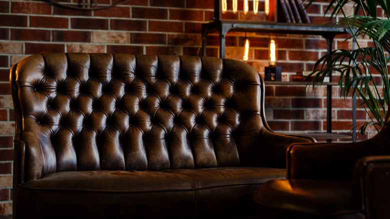 Doğal ışıkla tuğlaya karşı tutamlı koyu deri sandalye