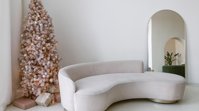 Bej modern bir kanepenin arkasında altın kemerli bir ayna