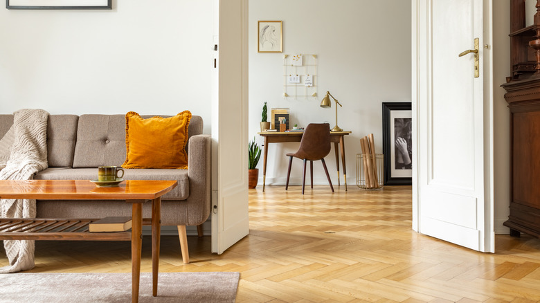 Sarı tonlu ahşap zeminler ve beyaz fransız kapılar ile oturma odası ve koridor