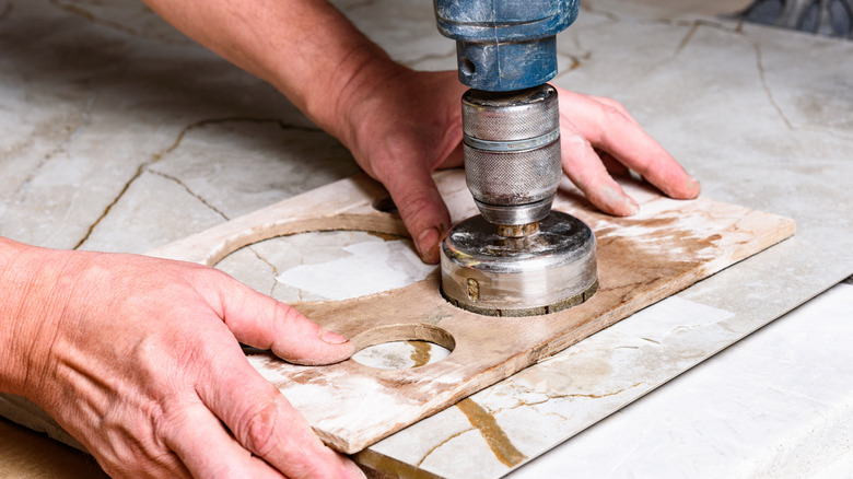 Elmas matkap ucu tarafından yapılan deliklerle kiremit tutan kişi