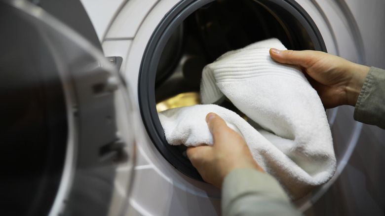 Eller Beyaz havluyu çamaşır makinesine koyuyor