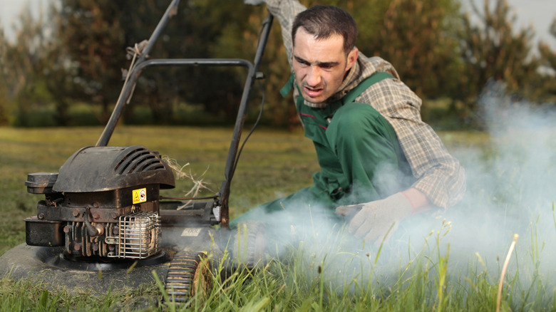 Adam sigara içen bir motorla çim biçme makinesi başlayan adam