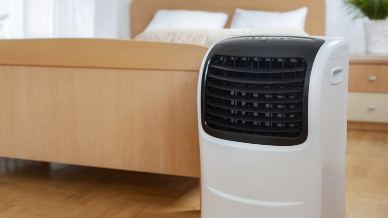 Ahşap yatağın önünde taşınabilir bir klima