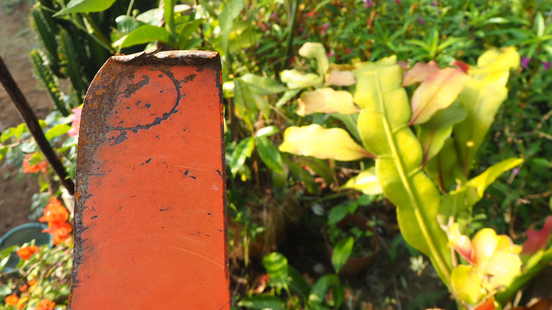 Bükülmüş çim biçme makinesi bıçağı tutan bir kişi