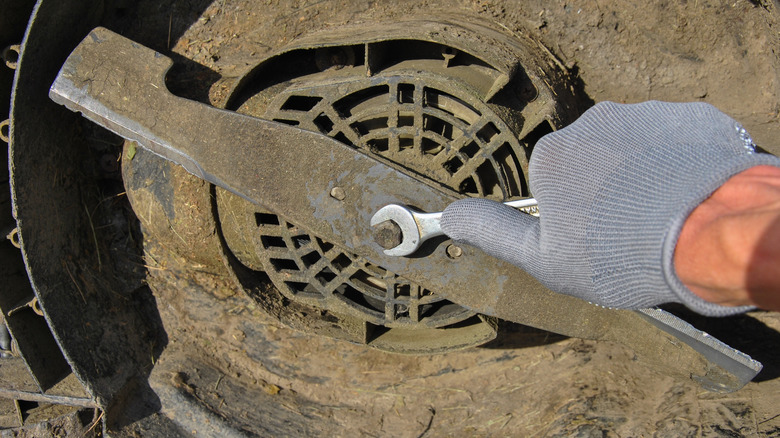 Çim biçme makinesi bıçağını kaldıran bir kişi