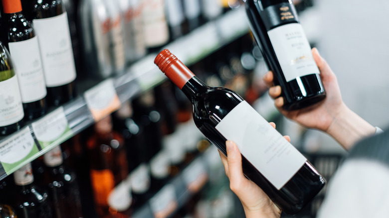 Kırmızı şarap şişesi tutan biri