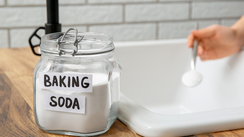 Lavabosunun tıkanması için kabartma tozu kullanan kadın