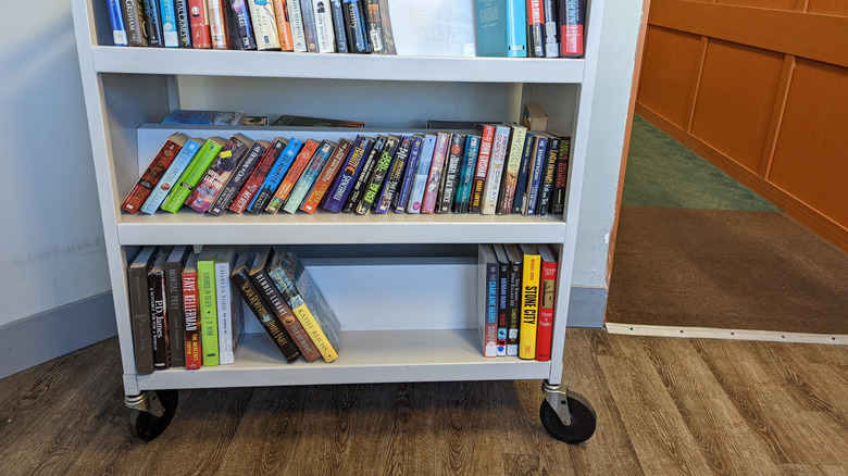 Beyaz kütüphane arabasına yaslanan kitaplar