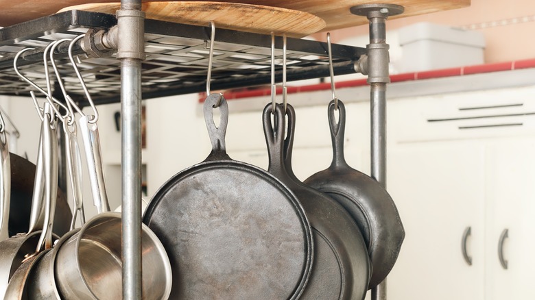 Asılı tencere ve tavalarla tavana monte bir raf.