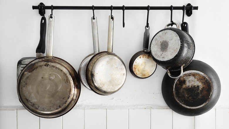 Kancalarla asılı tencere ve tavalarla duvara monte bir korkuluk.