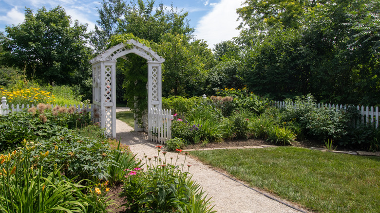 İki bahçe arasında çakıl bir yol üzerinde beyaz boyalı bir ahşap ağaç.