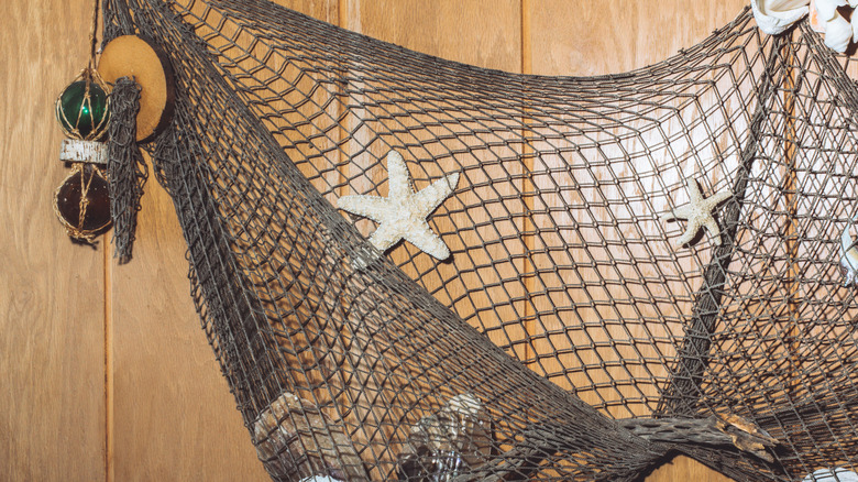 Fishnet ve denizyıldızı asılı bir ahşap panel duvarı.