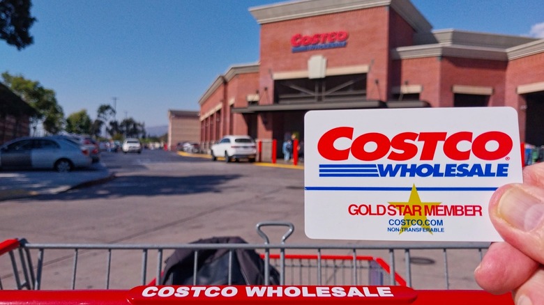 Uzakta bir Costco'nun önünde tutulan bir Costco Toptan Altın Yıldızlı Üye Kart.