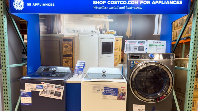 Costco'da, teslimat hizmetleri hakkında konuşan bir afişin altında satışa sunulabilecek çamaşır makinesi.